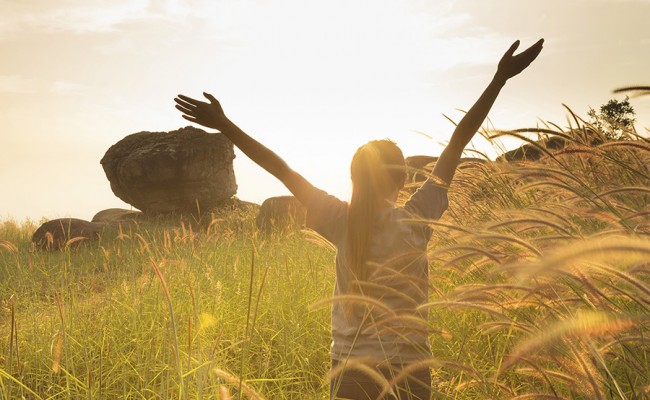 Young girl spreading hands with joy and inspiration facing the sun