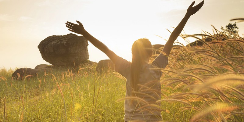 Young girl spreading hands with joy and inspiration facing the sun